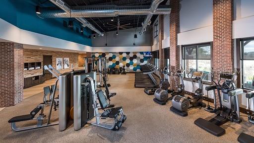 workout area featuring carpet, brick wall, and a high ceiling