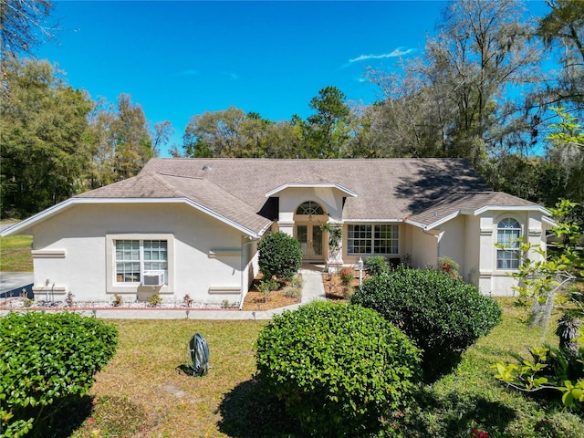 ranch-style home with roof with shingles, a front lawn, french doors, and stucco siding