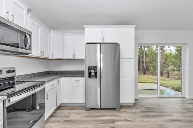 19925 SW Lark Dr, Dunnellon, FL 34431 - kitchen with appliances with stainless steel finishes, white cabinetry, light wood-style flooring, and dark stone counters