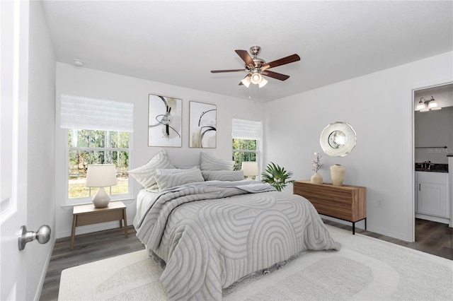 bedroom with ceiling fan, dark hardwood / wood-style flooring, sink, and ensuite bath