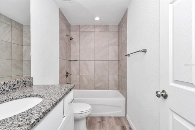 full bathroom featuring vanity, tiled shower / bath, toilet, a textured ceiling, and wood-type flooring