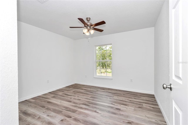 spare room with ceiling fan, light hardwood / wood-style floors, and a textured ceiling