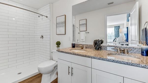 bathroom featuring tiled shower, vanity, and toilet