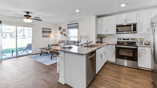 kitchen with kitchen peninsula, white cabinets, and appliances with stainless steel finishes