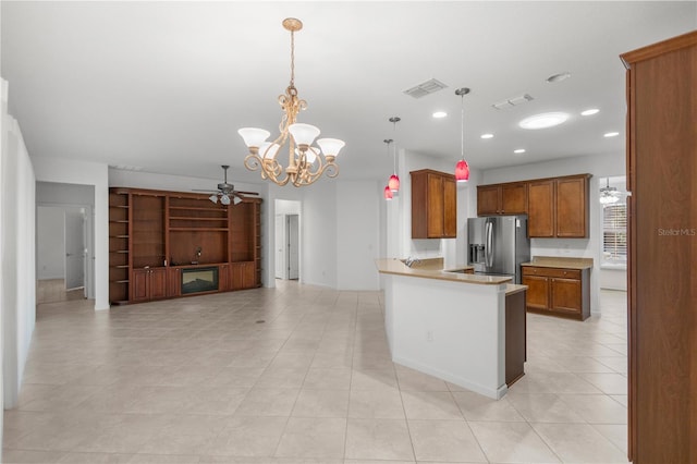 kitchen featuring kitchen peninsula, stainless steel fridge, decorative light fixtures, light tile patterned flooring, and ceiling fan with notable chandelier