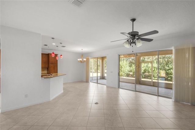 tiled empty room with ceiling fan with notable chandelier