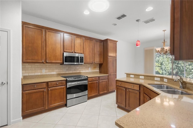 kitchen featuring sink, an inviting chandelier, light stone counters, pendant lighting, and appliances with stainless steel finishes