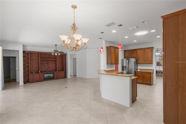 kitchen featuring kitchen peninsula, stainless steel fridge, ceiling fan with notable chandelier, and pendant lighting