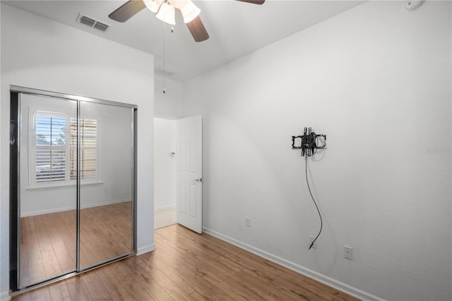 unfurnished bedroom with ceiling fan, a closet, and wood-type flooring