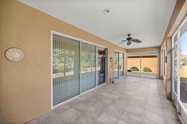 unfurnished sunroom with ceiling fan