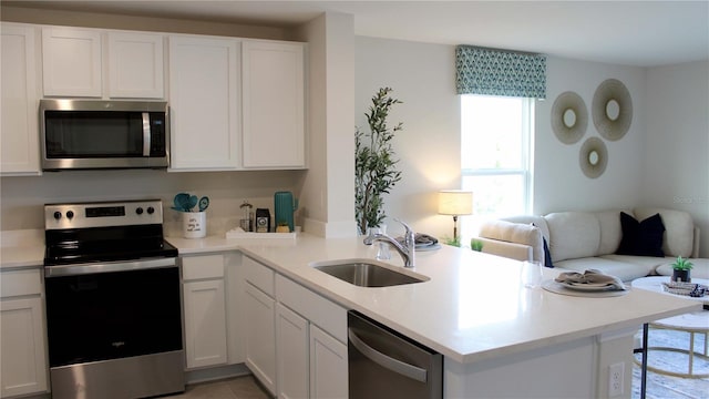 kitchen featuring kitchen peninsula, stainless steel appliances, white cabinets, and sink