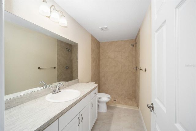 bathroom featuring tile patterned flooring, vanity, toilet, and tiled shower