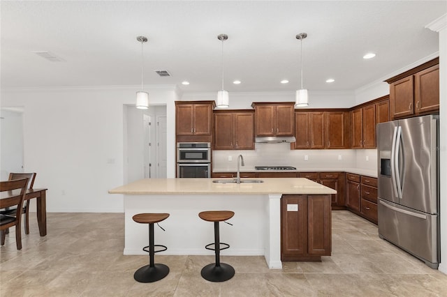 kitchen featuring sink, stainless steel appliances, pendant lighting, a breakfast bar, and a center island with sink