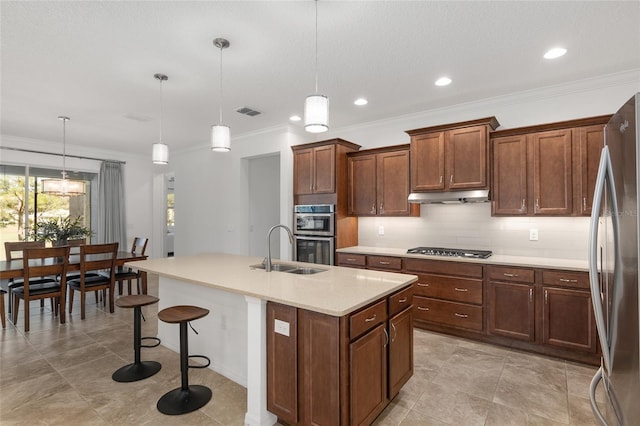 kitchen with a center island with sink, sink, hanging light fixtures, and appliances with stainless steel finishes