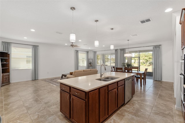 kitchen featuring a kitchen island with sink, sink, stainless steel dishwasher, ceiling fan, and decorative light fixtures