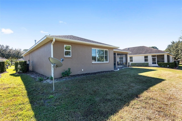 rear view of property with a lawn and a sunroom