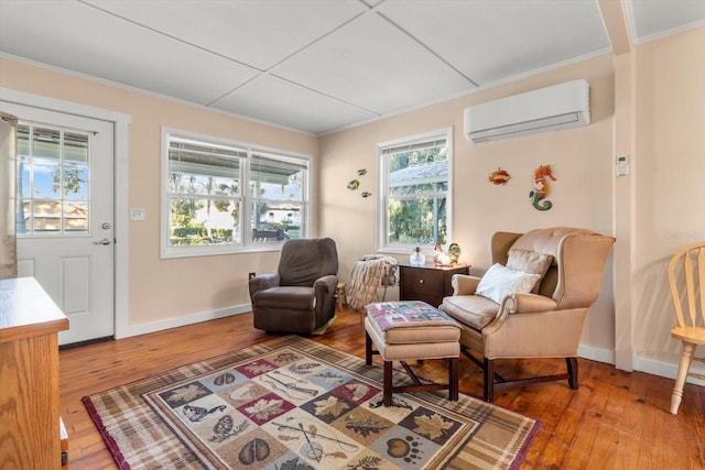 living area with a wall mounted AC, crown molding, and hardwood / wood-style flooring