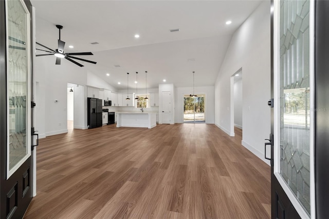 unfurnished living room featuring hardwood / wood-style floors, ceiling fan, and high vaulted ceiling