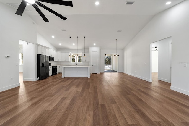 unfurnished living room featuring hardwood / wood-style floors, ceiling fan, and high vaulted ceiling