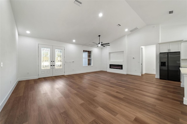 unfurnished living room with hardwood / wood-style flooring, ceiling fan, high vaulted ceiling, and french doors