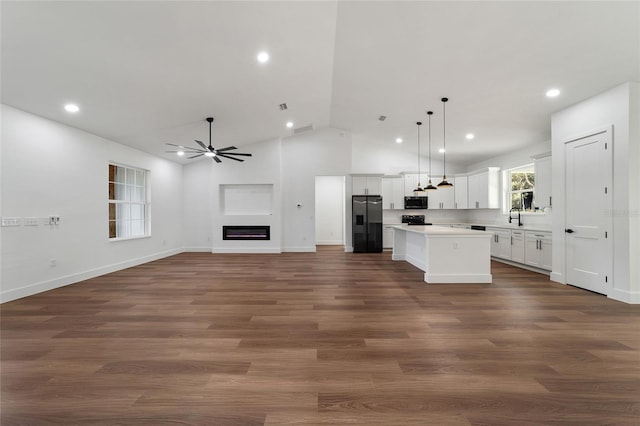 kitchen with white cabinets, sink, vaulted ceiling, refrigerator with ice dispenser, and a kitchen island