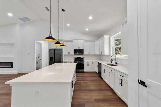 kitchen with black appliances, sink, vaulted ceiling, decorative light fixtures, and a kitchen island