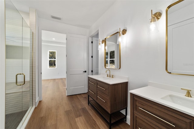 bathroom with hardwood / wood-style floors, vanity, and a shower with door