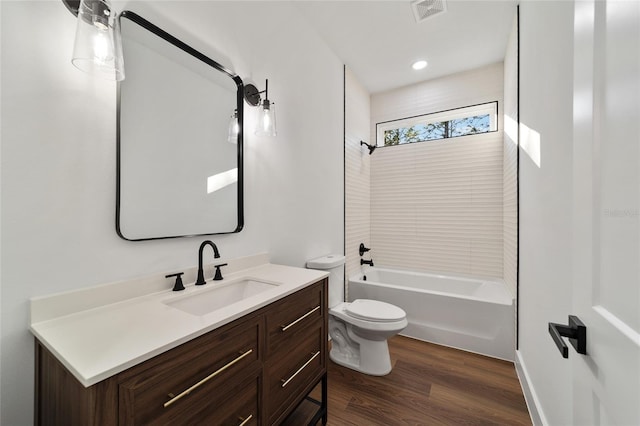 full bathroom featuring hardwood / wood-style floors, vanity, tiled shower / bath combo, and toilet