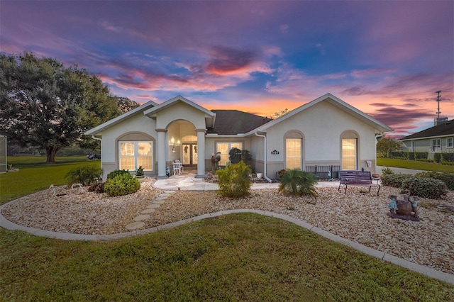 single story home featuring covered porch and a lawn