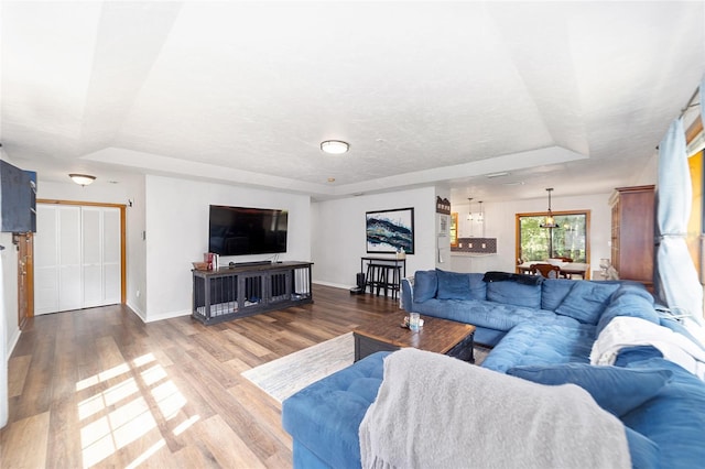 living room featuring hardwood / wood-style floors, a textured ceiling, and a tray ceiling