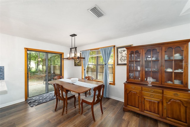 dining space featuring an inviting chandelier, plenty of natural light, and dark wood-type flooring