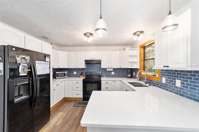 kitchen with black appliances, pendant lighting, white cabinetry, and sink