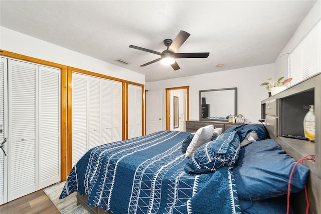 bedroom featuring hardwood / wood-style floors, ceiling fan, and two closets