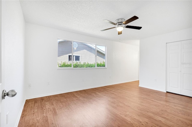 unfurnished room featuring ceiling fan, light hardwood / wood-style floors, and a textured ceiling