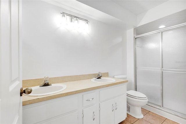 bathroom featuring tile patterned floors, vanity, toilet, and a shower with shower door