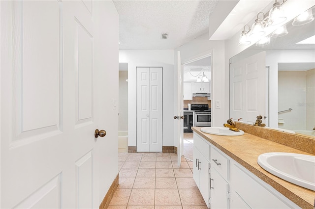 bathroom with vanity, a textured ceiling, tile patterned floors, and a washtub