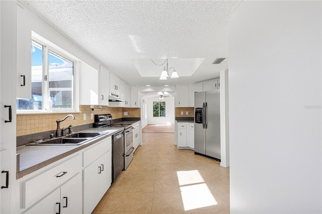 kitchen featuring white cabinetry, sink, hanging light fixtures, stainless steel appliances, and ceiling fan with notable chandelier