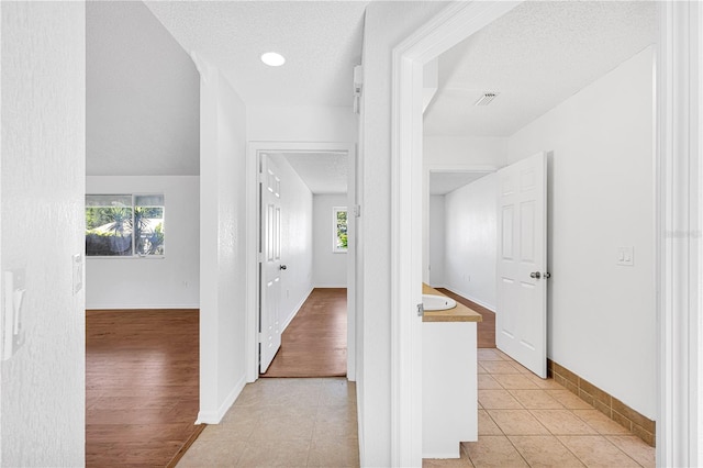 hallway featuring light hardwood / wood-style floors and a textured ceiling