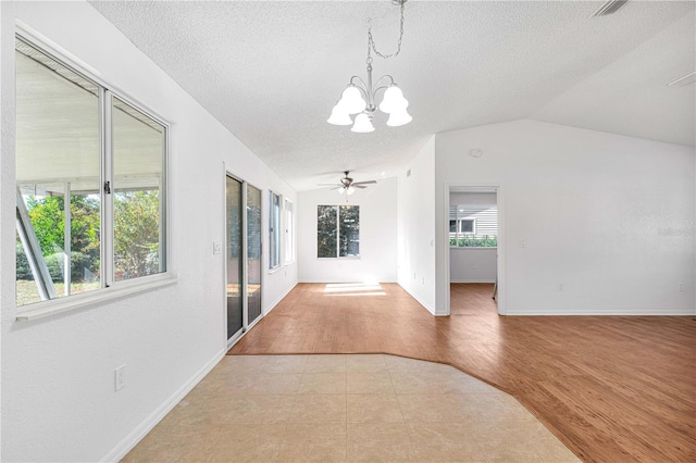 unfurnished room with a textured ceiling, light hardwood / wood-style floors, lofted ceiling, and a healthy amount of sunlight