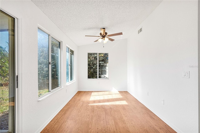 unfurnished room featuring a textured ceiling, ceiling fan, light hardwood / wood-style flooring, and vaulted ceiling