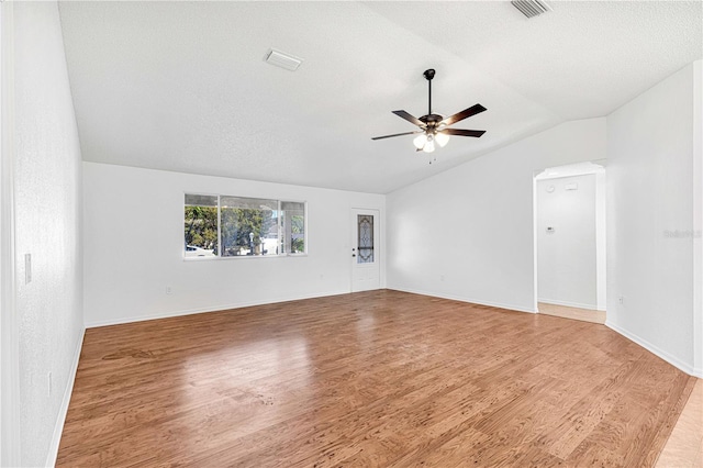 spare room featuring a textured ceiling, ceiling fan, light hardwood / wood-style flooring, and vaulted ceiling