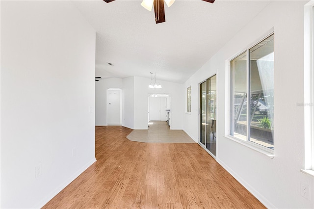 hall featuring a textured ceiling, light hardwood / wood-style flooring, vaulted ceiling, and a notable chandelier