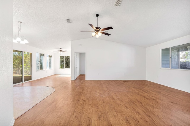 unfurnished living room with a textured ceiling, ceiling fan with notable chandelier, wood-type flooring, and vaulted ceiling