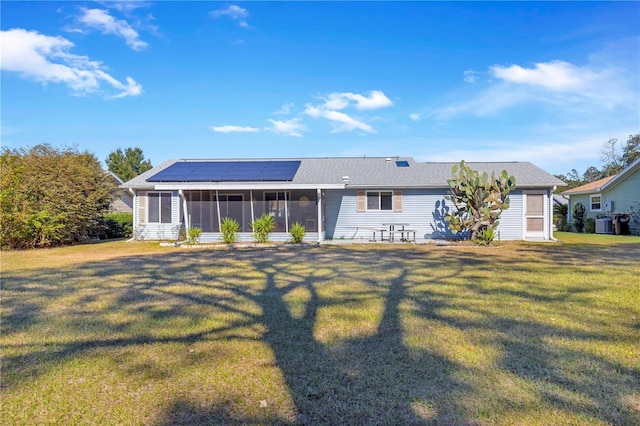 rear view of property featuring solar panels, a yard, and a sunroom