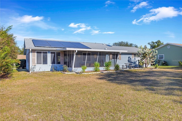 back of house with solar panels, a yard, and a sunroom