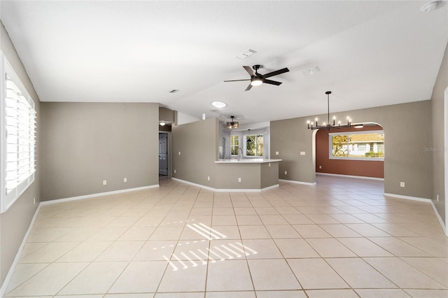 unfurnished living room featuring ceiling fan with notable chandelier, light tile patterned floors, sink, and vaulted ceiling