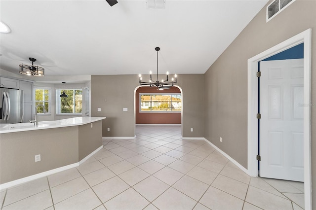 unfurnished dining area featuring plenty of natural light, light tile patterned floors, ceiling fan with notable chandelier, and sink