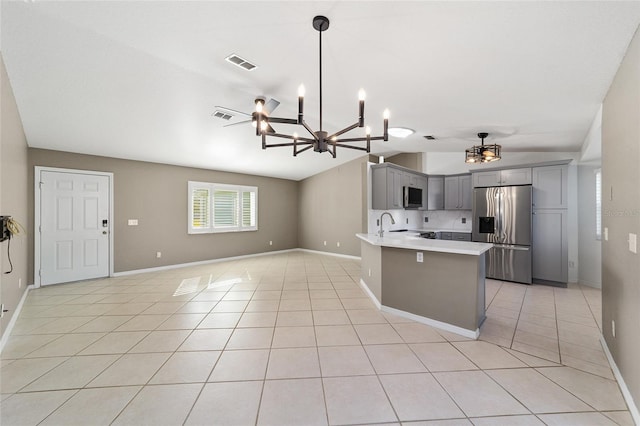 kitchen featuring gray cabinetry, hanging light fixtures, vaulted ceiling, light tile patterned flooring, and stainless steel appliances