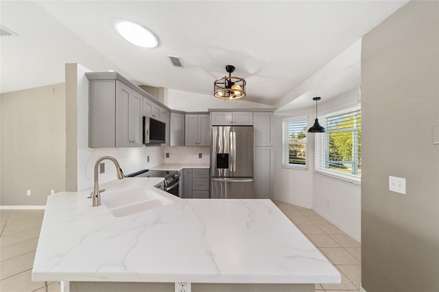 kitchen with kitchen peninsula, appliances with stainless steel finishes, gray cabinetry, sink, and pendant lighting