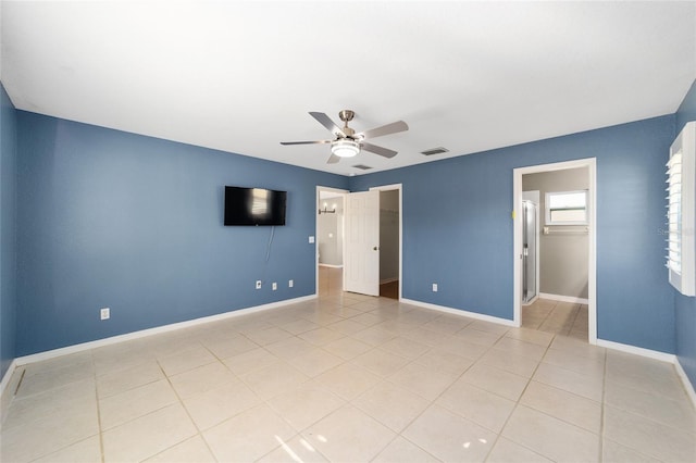 unfurnished bedroom featuring ceiling fan, light tile patterned flooring, a walk in closet, and a closet